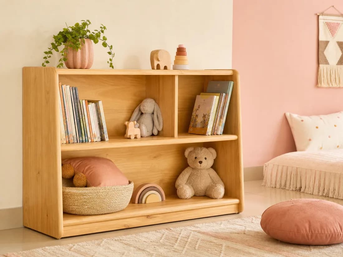 Photograph of a rounded low light solid-wood bookshelf with children’s books, toys and baskets